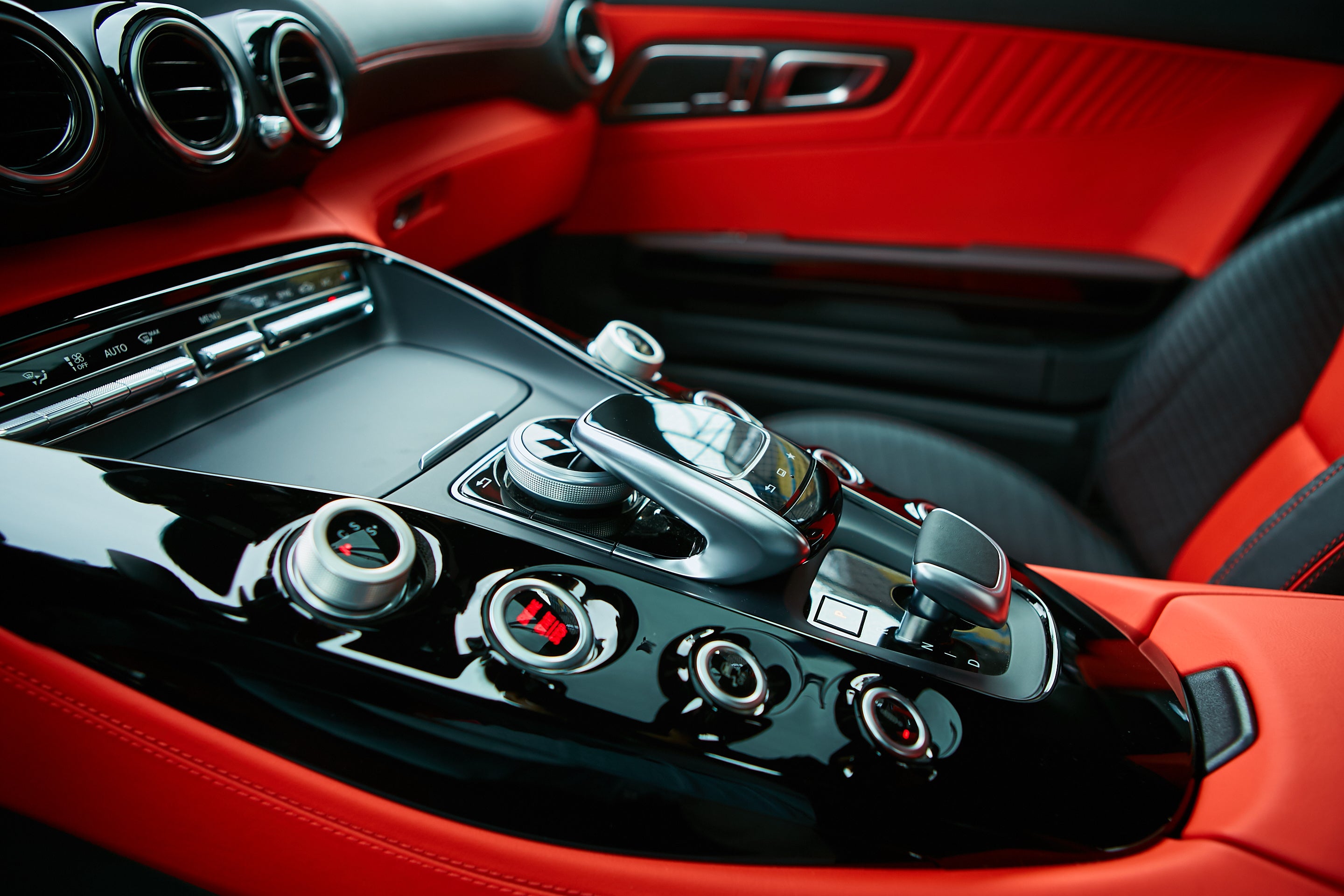 Close-up of a car's red interior with a focus on the dashboard and steering wheel controls.