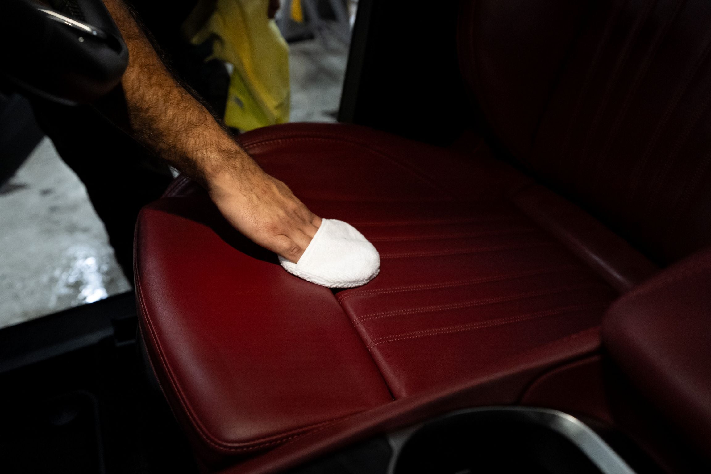 GenTek leather protection being applied by hand to a red leather car seat.