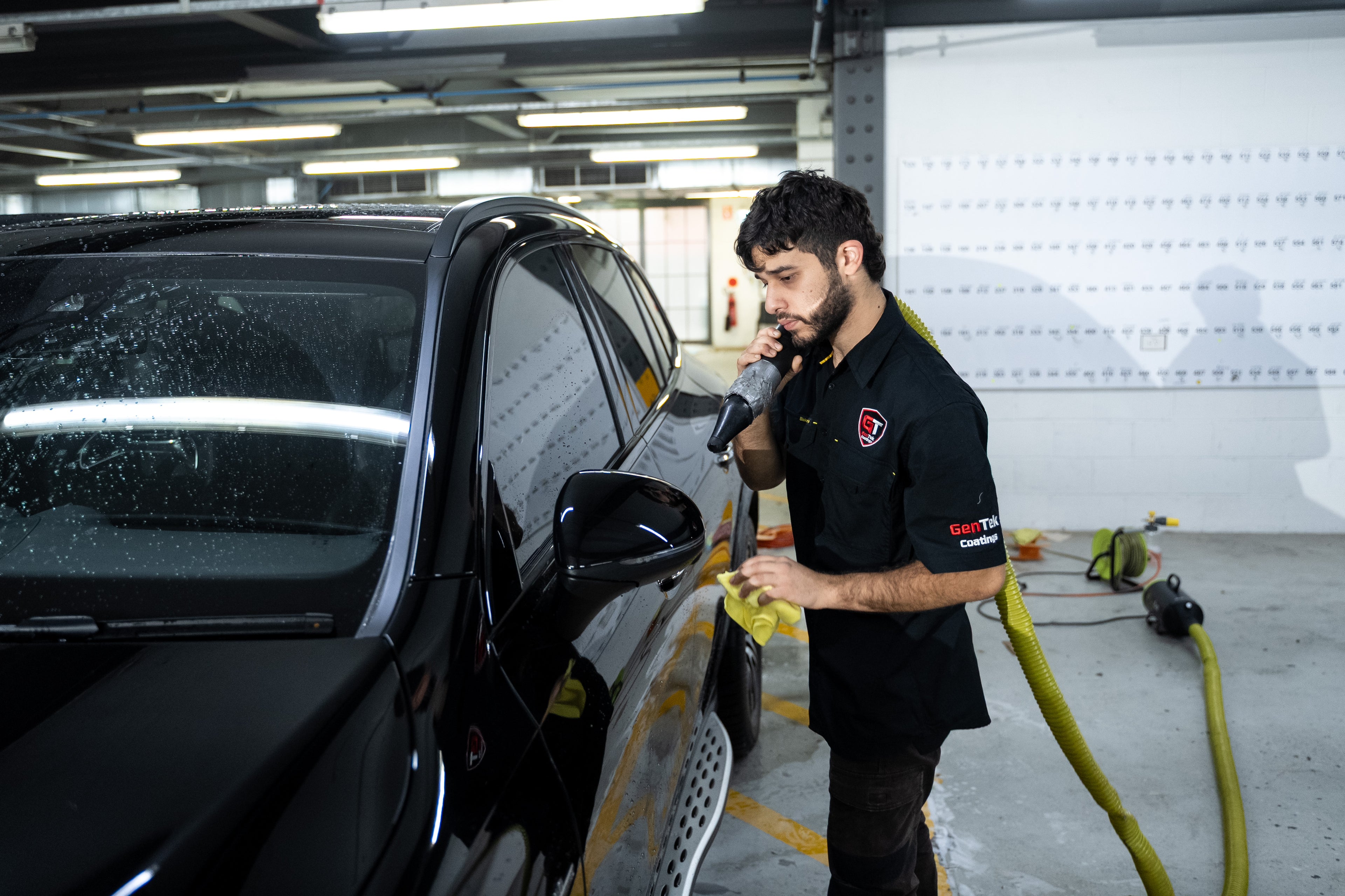 Black SUV with professionally tinted windows being carefully finished by a GenTek technician.
