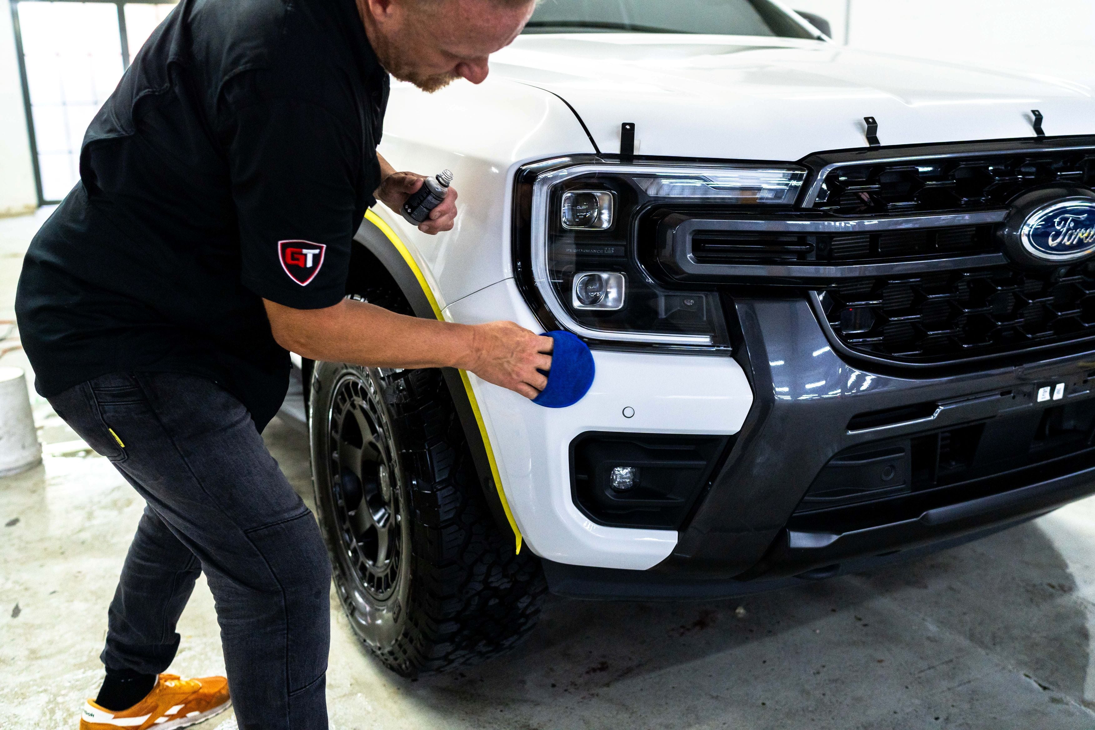 GenTek technician applying ceramic coating to the front paintwork of a white Ford ute.