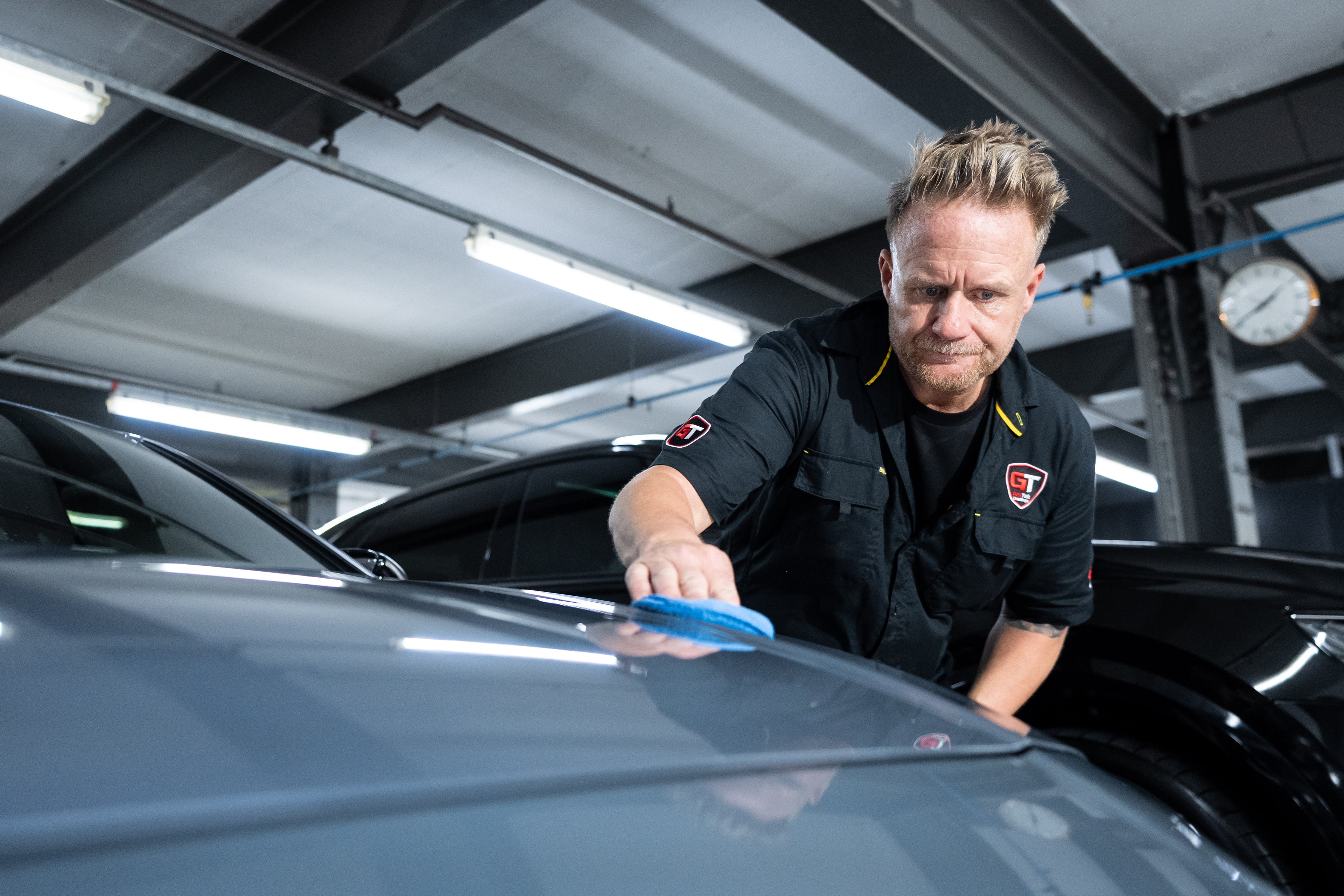 GenTek technician applying ceramic coating by hand to the bonnet of a grey car.