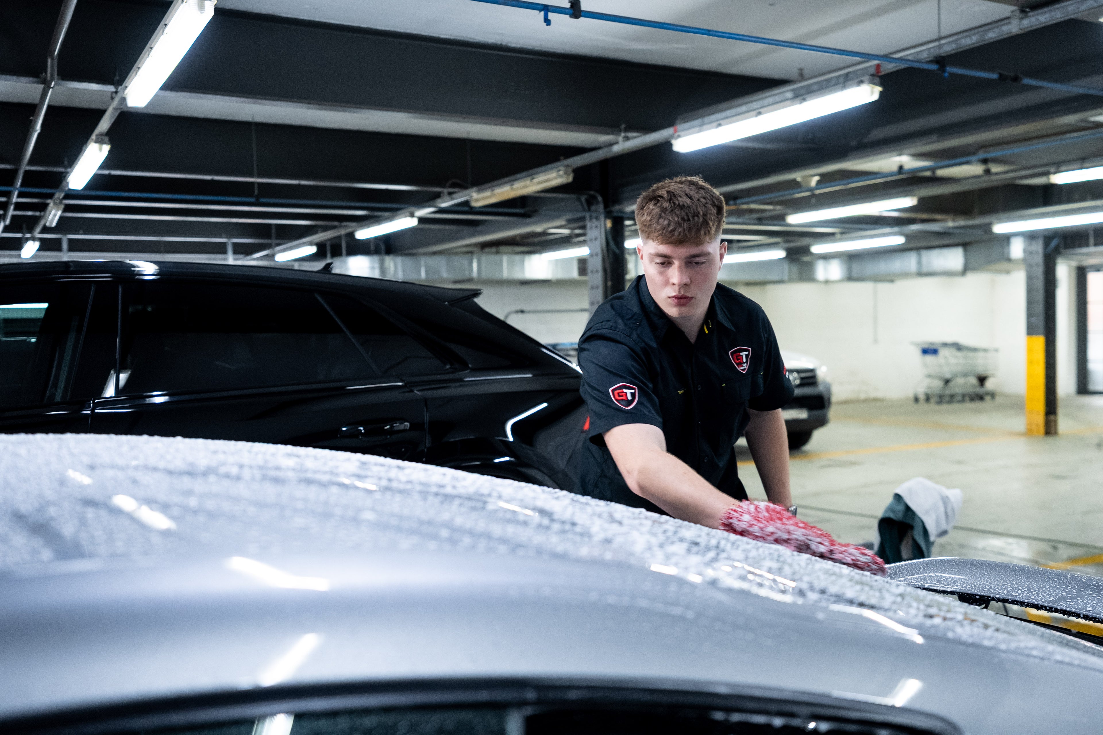 GenTek technician hand washing a silver car during the paint preparation process.