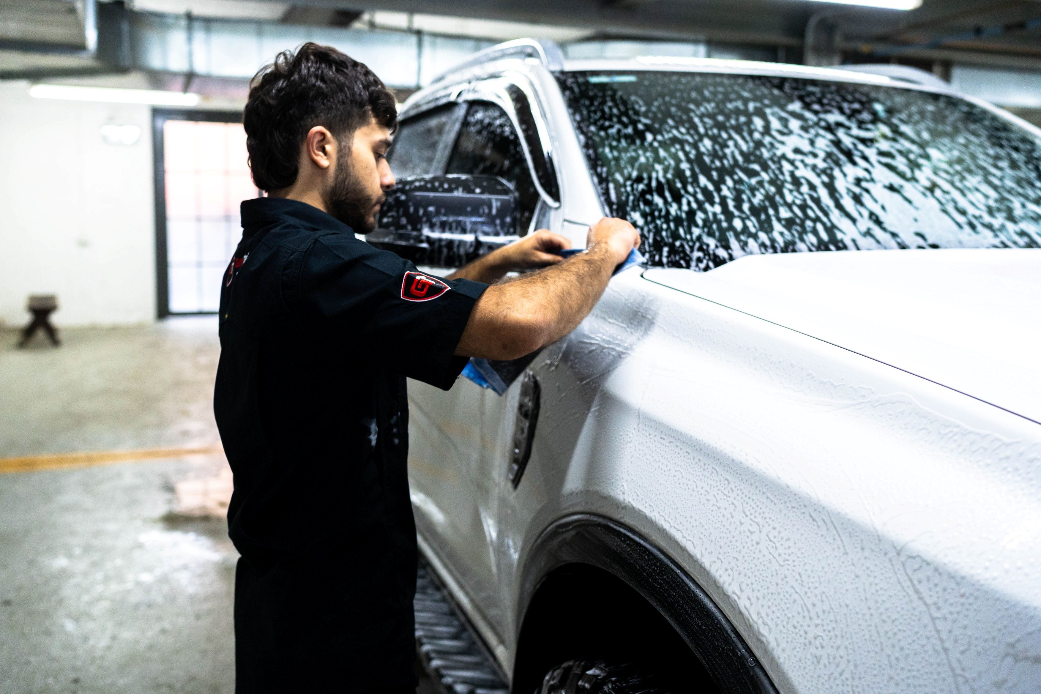 GenTek technician hand washing a white ute during professional ceramic coating preparation.