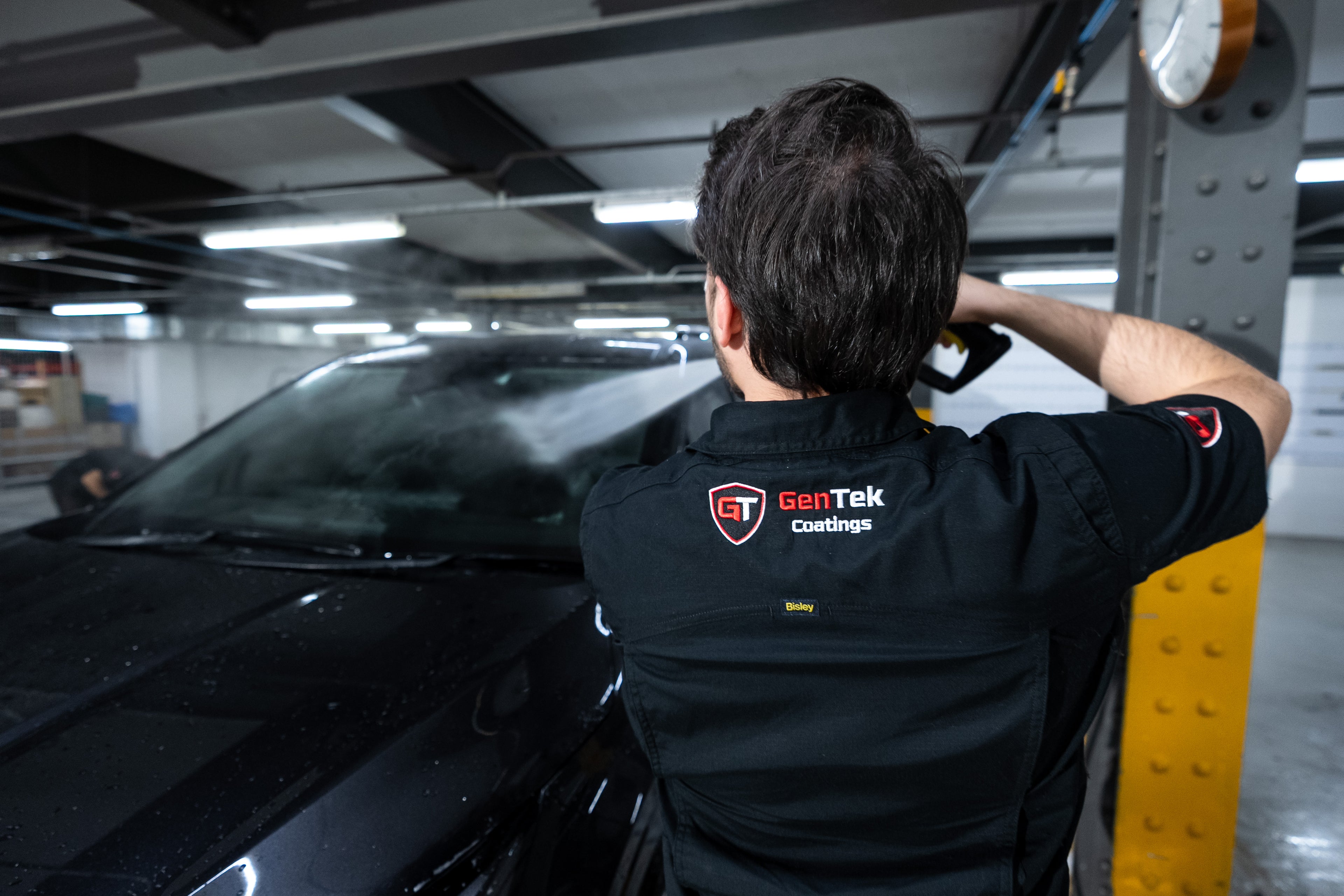 GenTek technician preparing a black car for professional ceramic paint protection application.