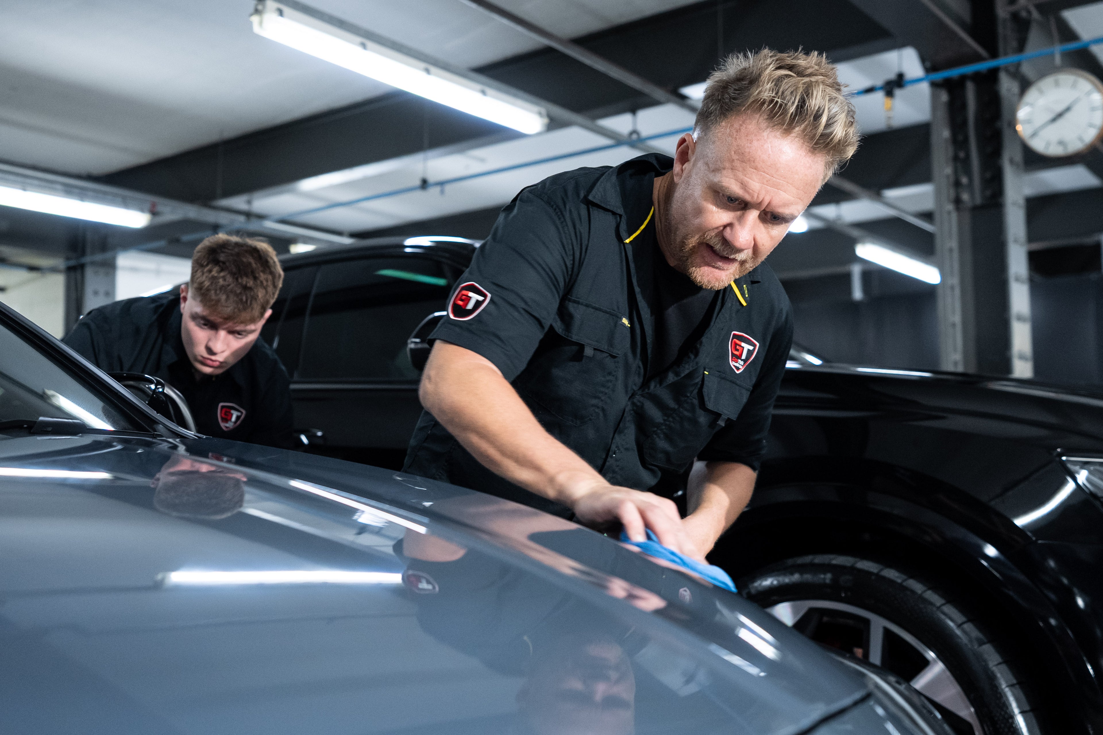 Two GenTek technicians professionally applying ceramic graphene ultra paint protection to a car.