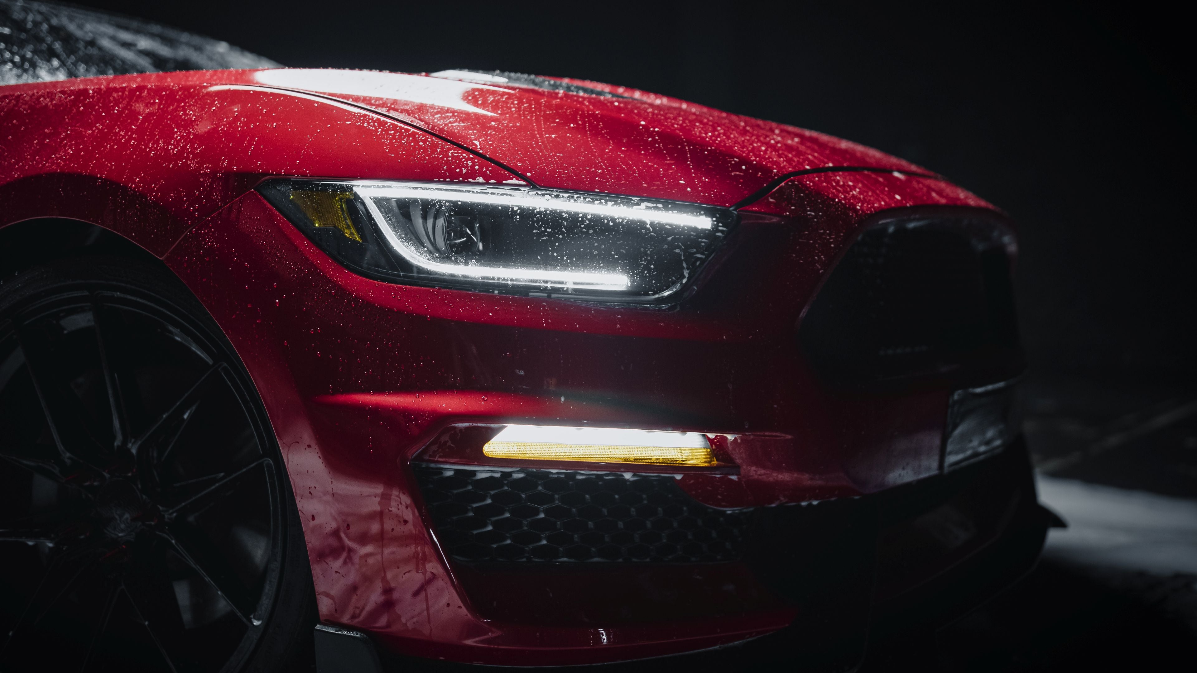 Close-up of a red sports car showing water beading across the ceramic-coated paintwork.