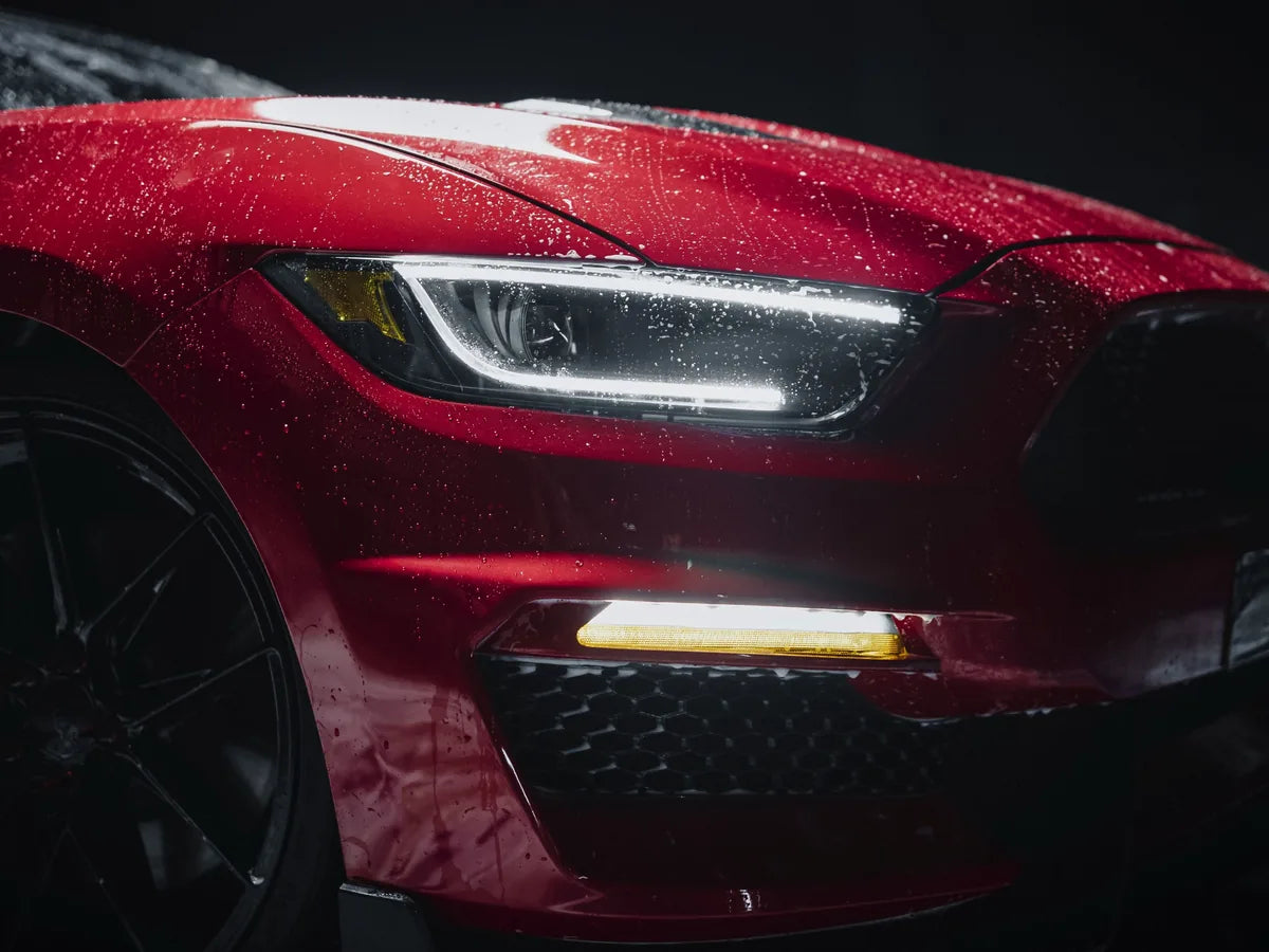 Water beading on the front of a red car after coating